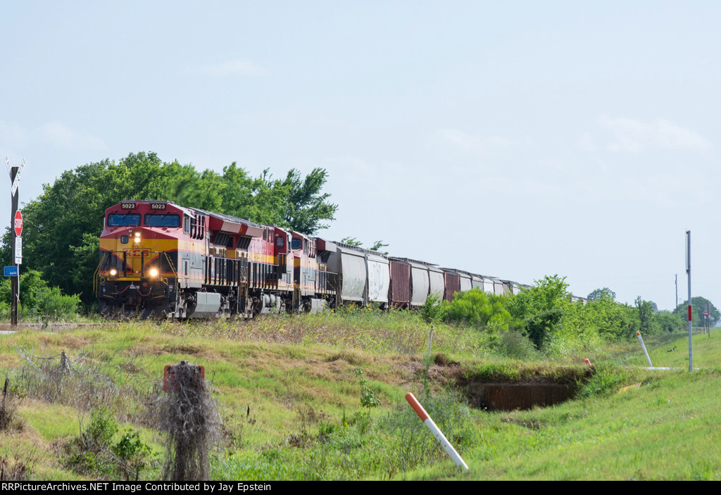 A northbounc grain train approaches a small crossing